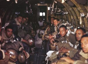 Paratrooper firefighters of the all-black airborne 555th Parachute Infantry Battalion in gear, sitting inside a plane waiting for their jumps
