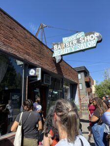 A group of people standing outside a barber shop.