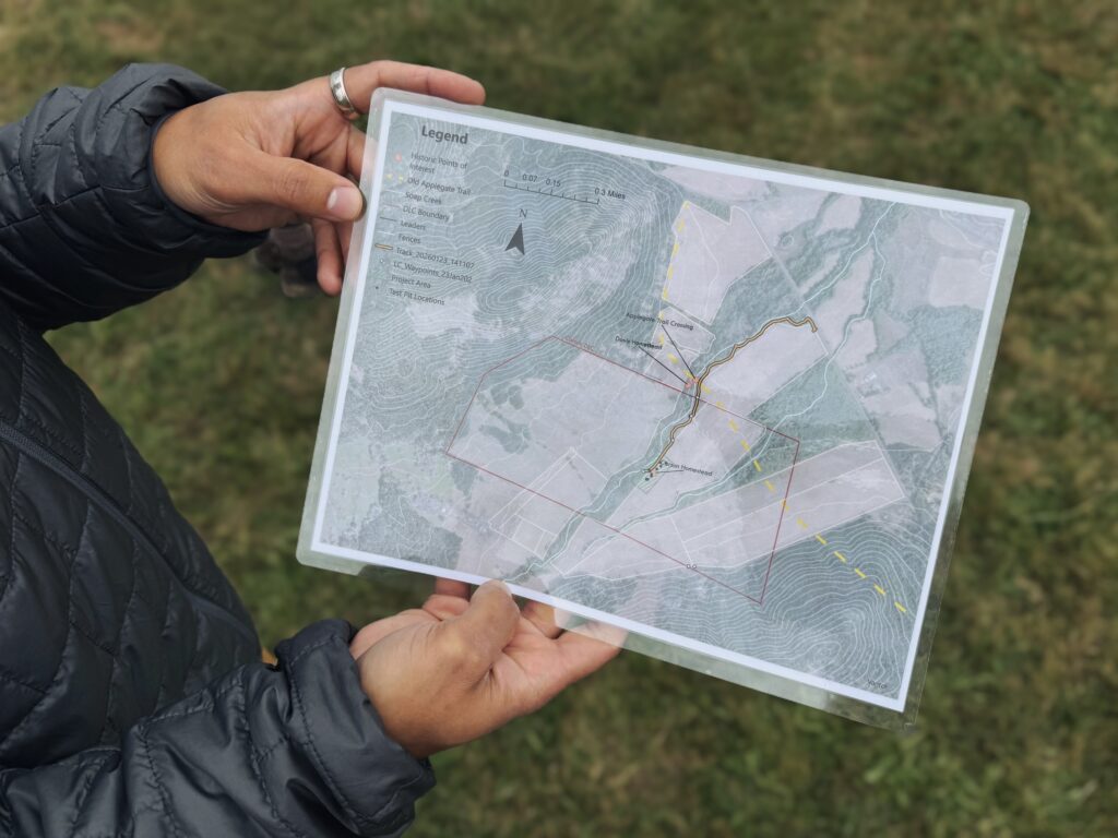 Person holding a laminated topographic map outdoors, showing various marked routes, boundaries, and a legend in the top left corner—perfect for those interested in exploring stories like the What is Letitia Carson Legacy Project News Newsletter?.
