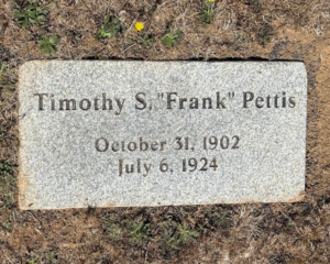 A gravestone reads: “Timothy S. ‘Frank’ Pettis, October 31, 1902, July 6, 1924,” on a patch of dry grass.